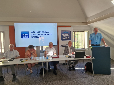 Eine Gruppe von Menschen nimmt an einer Präsentation in einem Konferenzraum teil, die sich mit der Wohnungsbaugenossenschaft Nord befasst.